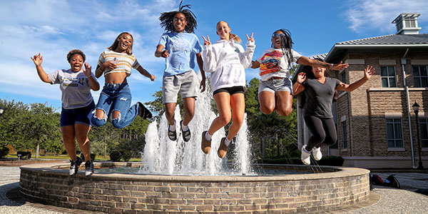students jumping in front of a fountain
